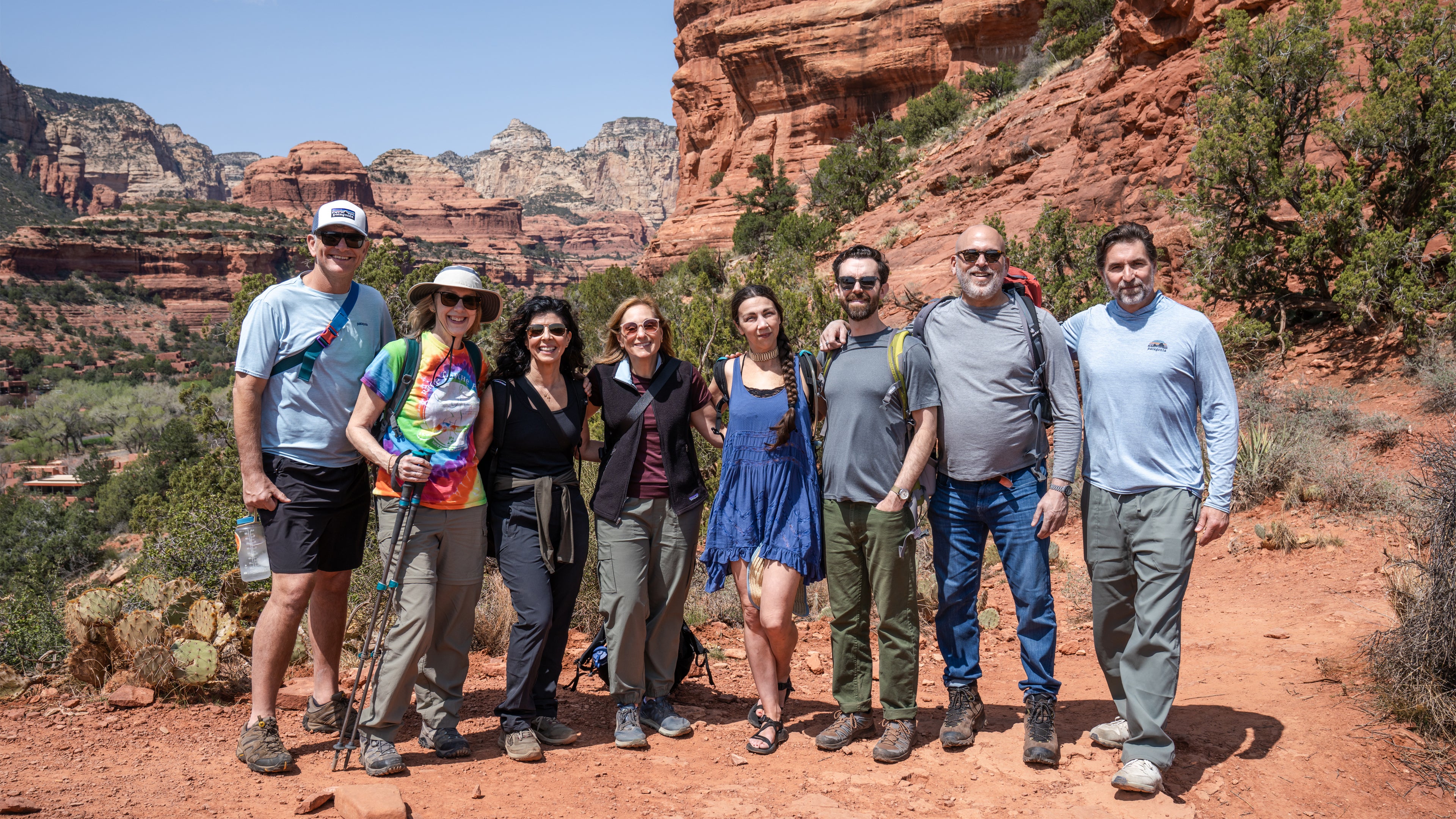 Group of people hiking in a desert landscape with red rock formations.
